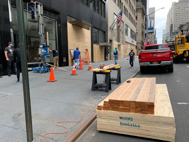 Workers board up stores along 5th Avenue in Manhattan on Tuesday.
